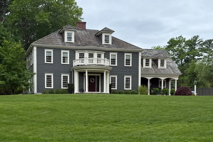 A large, stately two-story home rolling green lawn