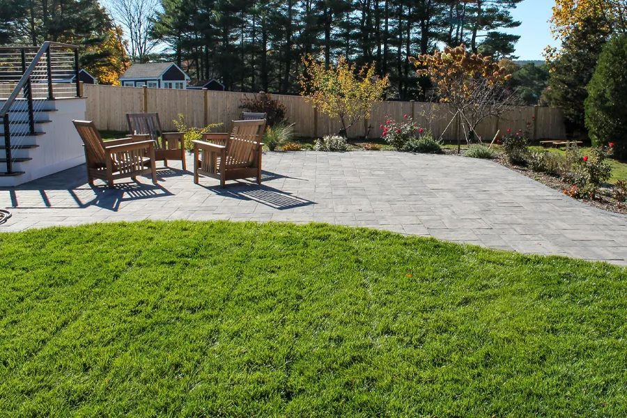 The patio is bordered by a bright, lush green lawn
